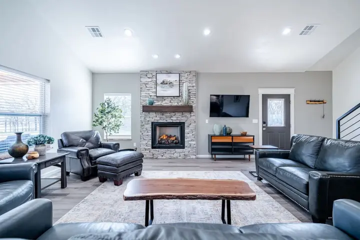 Living room with a stacked-stone fireplace, leather sofas and a live-edge coffee table