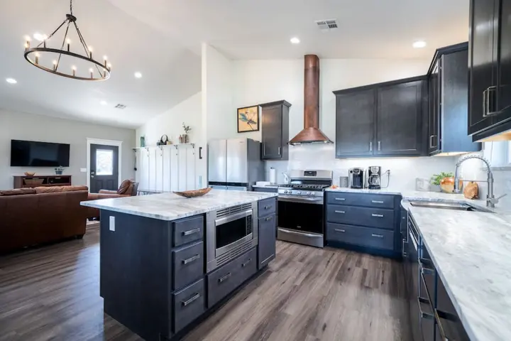 Open kitchen and living area with gas range and copper hood, enjoy a home cooked meal with a kitchen stocked with