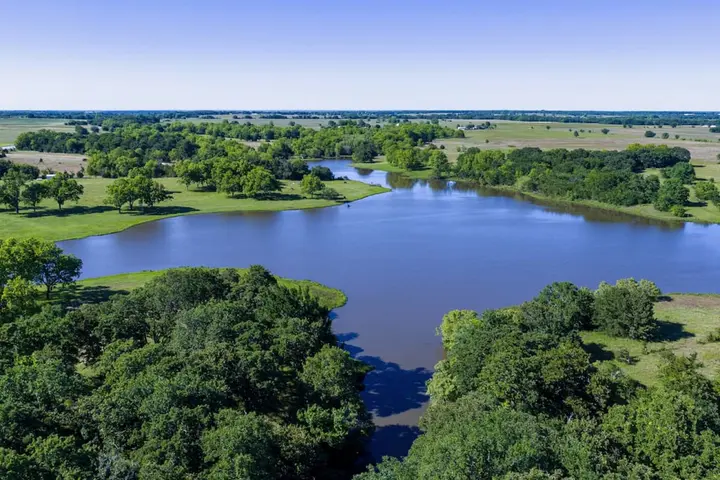 Aerial view of a lake winding through wooded farmland
