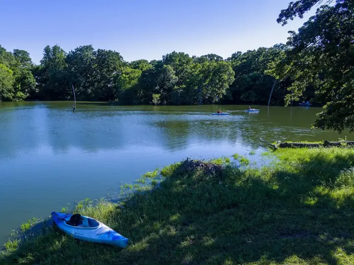 Kayak on the grassy bank of a tree-lined pond