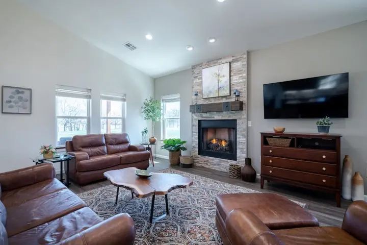 Living room with leather sofas, a live-edge coffee table and a lit stone fireplace