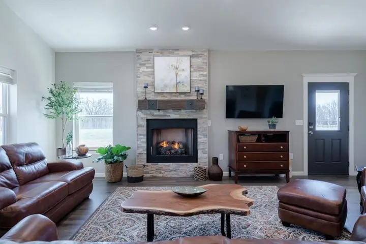 Living room with leather sofa and ottoman facing the stone fireplace
