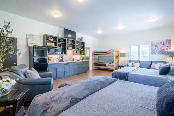 One Bedroom efficiency suite with open floor plan, two queen beds, bunk bed, a sofa and a kitchenette