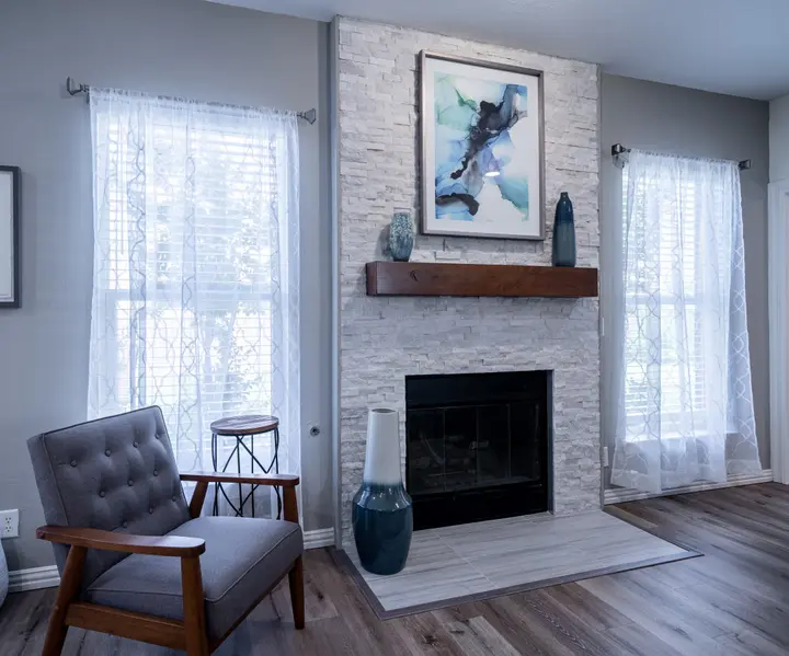 Sitting area with a stone fireplace, wood mantel and a mid-century armchair