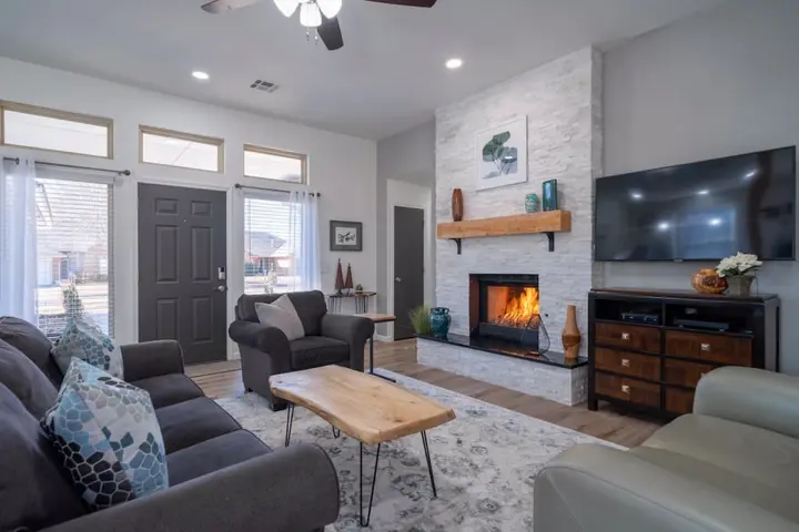Living room with a stone fireplace, wood mantel, live-edge coffee table and grey sofas