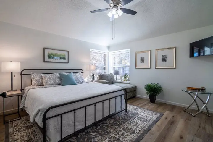 Bedroom with a black iron king bed, wall TV and a corner window seat