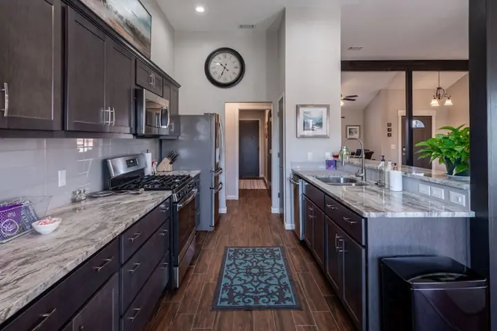 Galley kitchen with dark cabinets, granite counters and a gas range