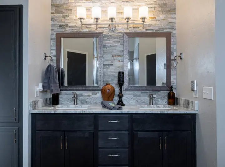 Bathroom double vanity with two mirrors against a stacked-stone wall