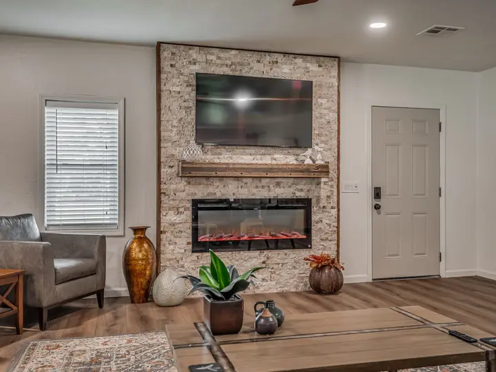 Stacked-stone wall with an electric fireplace and wall-mounted TV