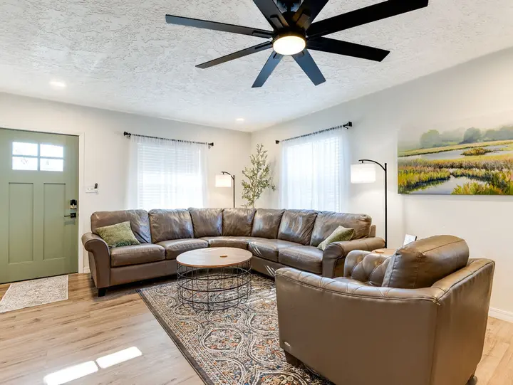 Living room with a leather sectional, round coffee table and the green front door