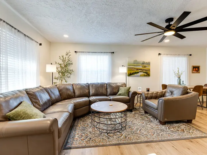 Living room with a leather sectional and armchair under a large ceiling fan