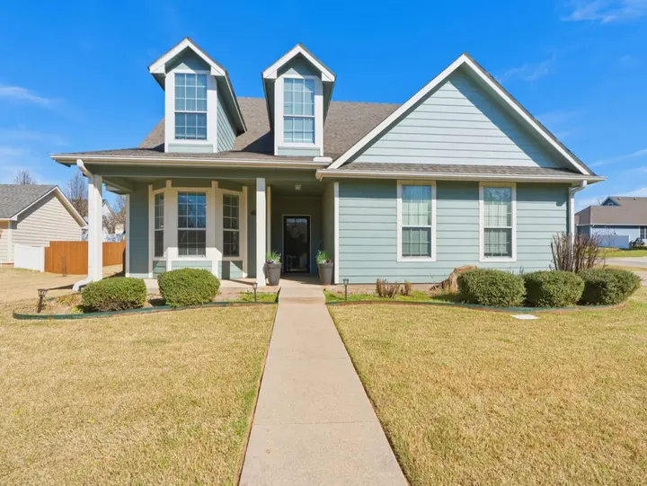 Emily House, a blue two-story home with dormer windows and a front porch, set on a quiet, safe street in Ada where you can walk up to a warm welcome