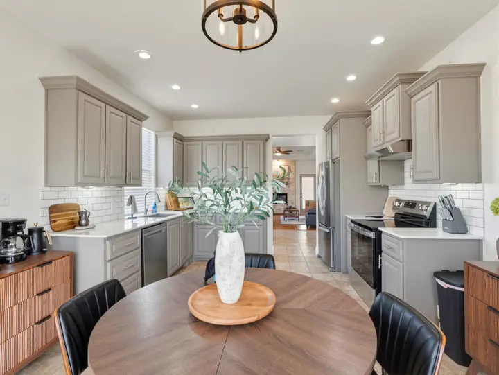 Fully equipped kitchen with grey cabinets, a coffee station, and a round dining table for four